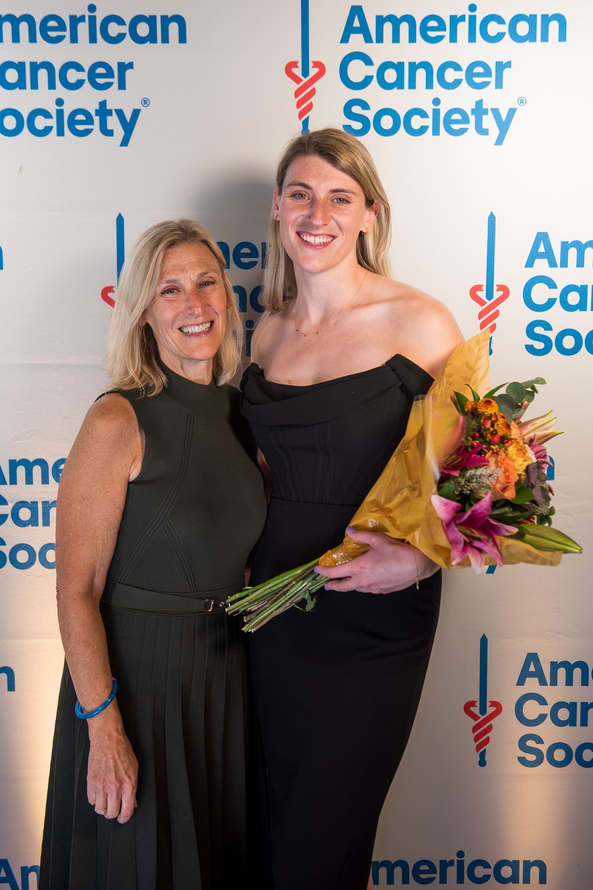 Two women with a bouquet at a charity gala