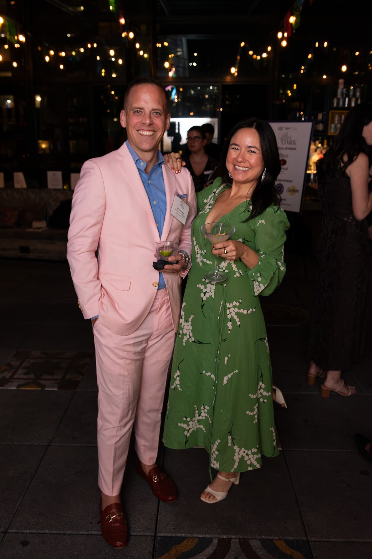 A couple in pink and green on a lantern-lit terrace