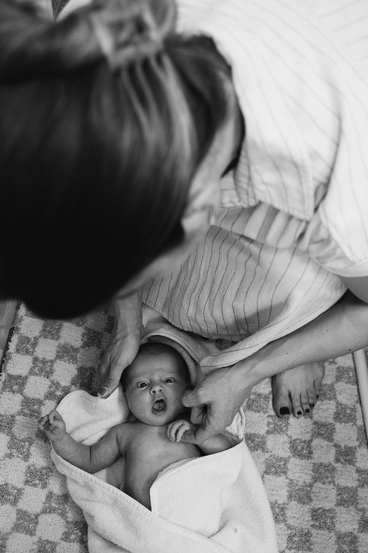 Newborn on a checked blanket, in black and white