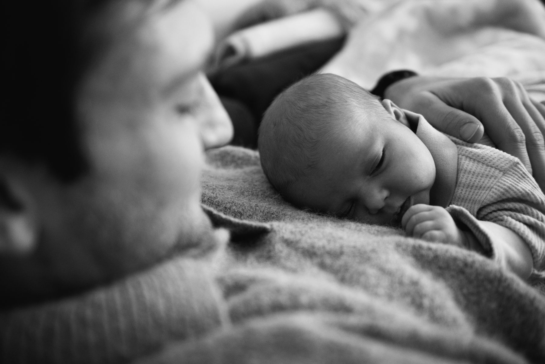 Father and newborn asleep, in black and white