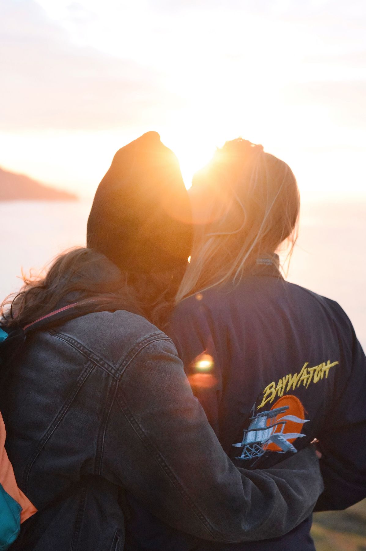 Two friends embracing at sunset