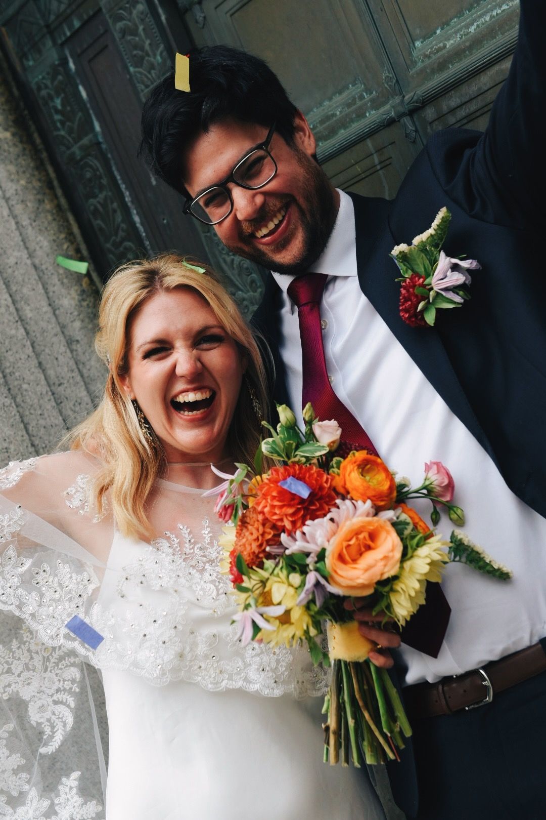 The couple laughing together, bouquet in hand