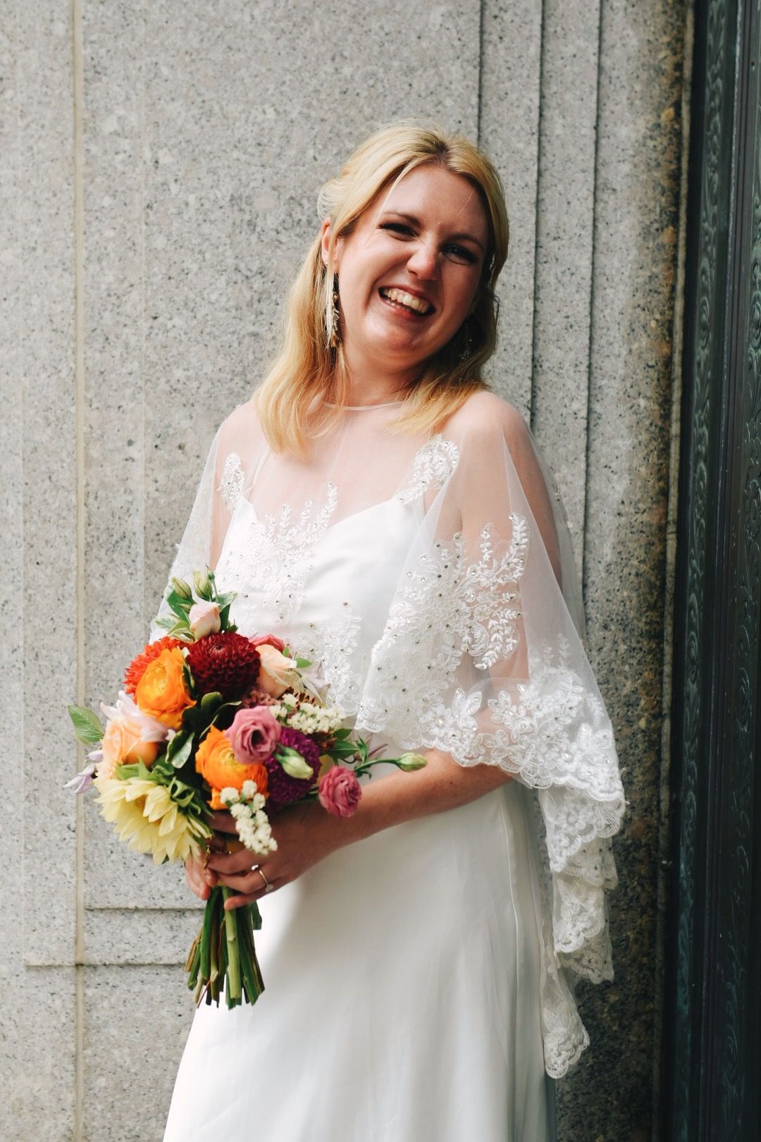 Bride laughing against a stone wall